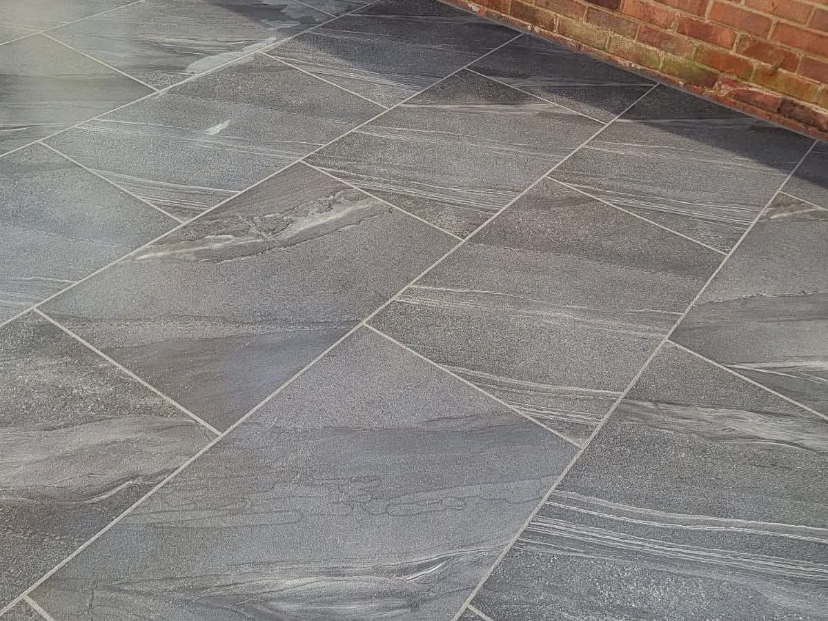 Grey sandstone patio slabs laid up to a brick wall