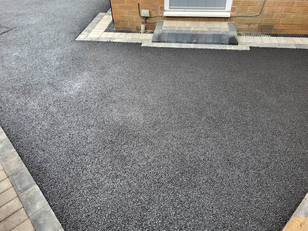 Freshly laid tarmac driveway with a block border and a step up to the door